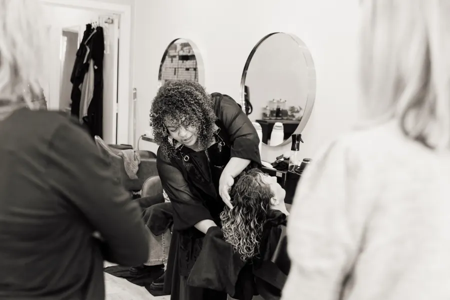 Caroline Smalley styling a curly-haired guest during an education session
